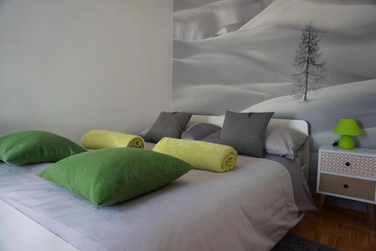 Velika zakonska postelja z zelenimi blazinami v zgornji etaži apartmaja Mistični gozd