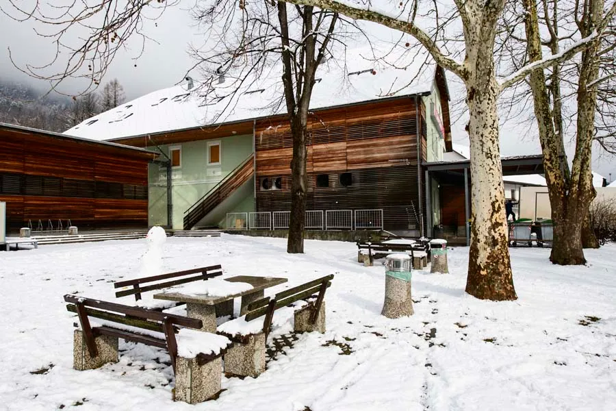 Park pred našo hišo pozimi, s klopmi in mizami pod snegom