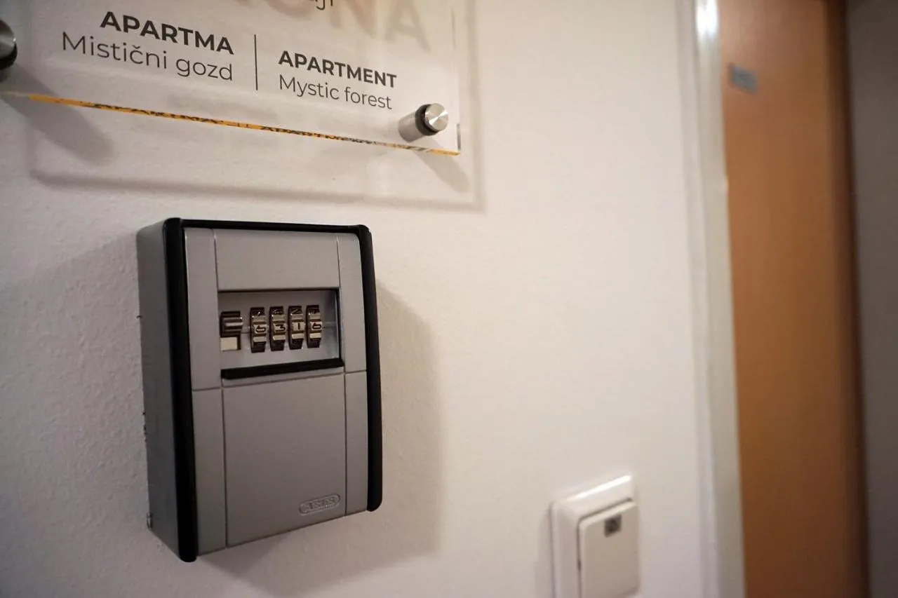 Tablica z imenom apartmaja Mistični gozd in skrinjica za ključ s kodo ob vratih