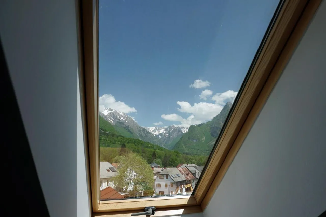 Gore nad Bovcem in strehe hiš skozi strešno okno apartmaja